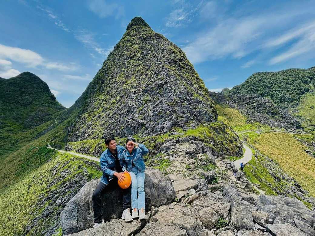A couple taking a photo together in front of Ha Giang's majestic limestone mountains