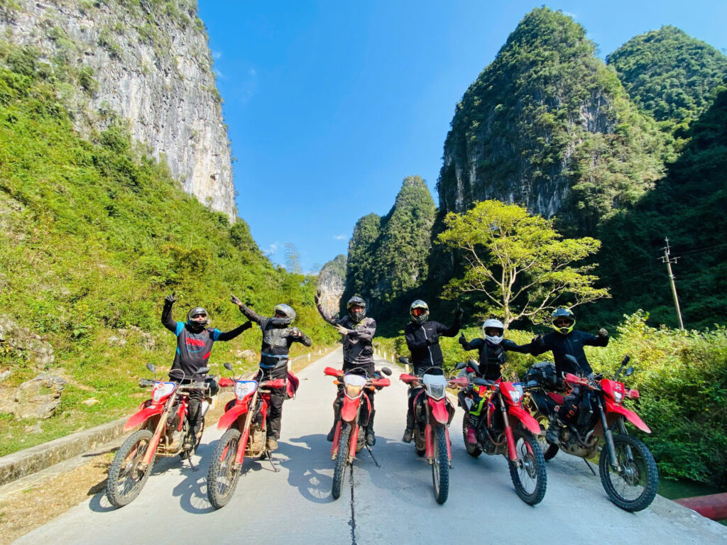 Motorcyclist riding a dirt bike along rocky terrain and steep slopes in Ha Giang