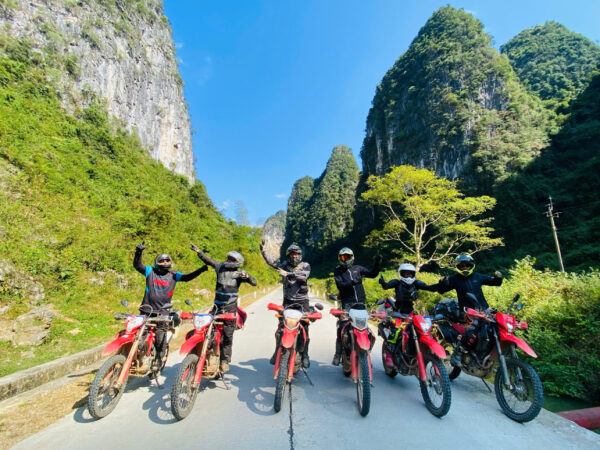 Motorcyclist riding a dirt bike along rocky terrain and steep slopes in Ha Giang