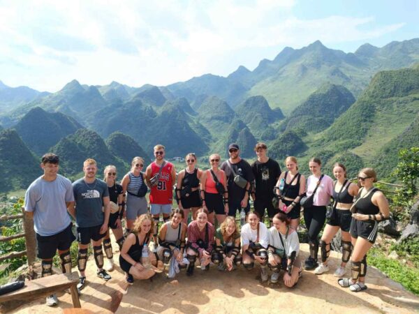 Group of travelers taking a photo with majestic mountains in the background during their Ha Giang tour